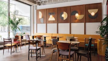 A modern interior with wooden furniture, a large window, and a wall with geometric light fixtures.