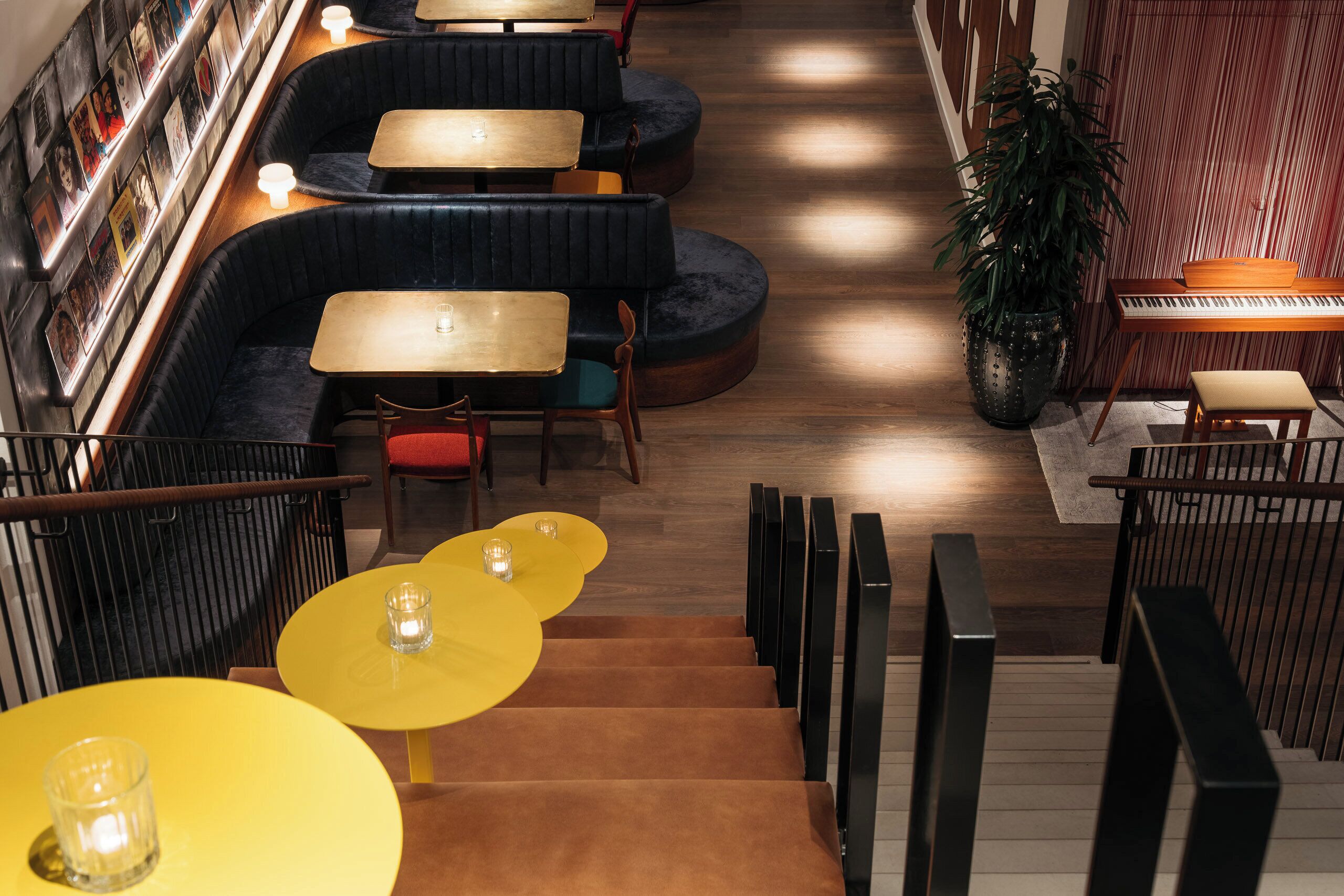 A modern interior with seating areas, a piano, and a staircase.
