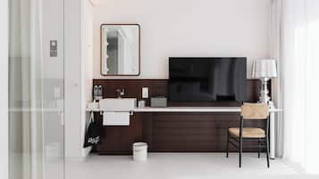 Habitación de hotel moderna con un televisor de pantalla plana grande, un tocador con espejo, una silla y un escritorio.