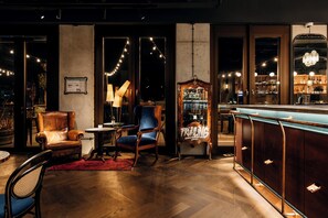 Una zona de bar con mobiliario de madera, un tapete rojo y luces colgantes.