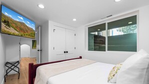 Una camera da letto con un letto, una TV a parete, un armadio e una finestra vista.