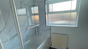 Un baño con bañera, ventana y pared de mármol.