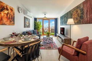 A modern living room with a dining area, a sofa, a TV, and a balcony with a view. - 5min to Taksim, Bosphorus View & Terrace (ISTANBUL)