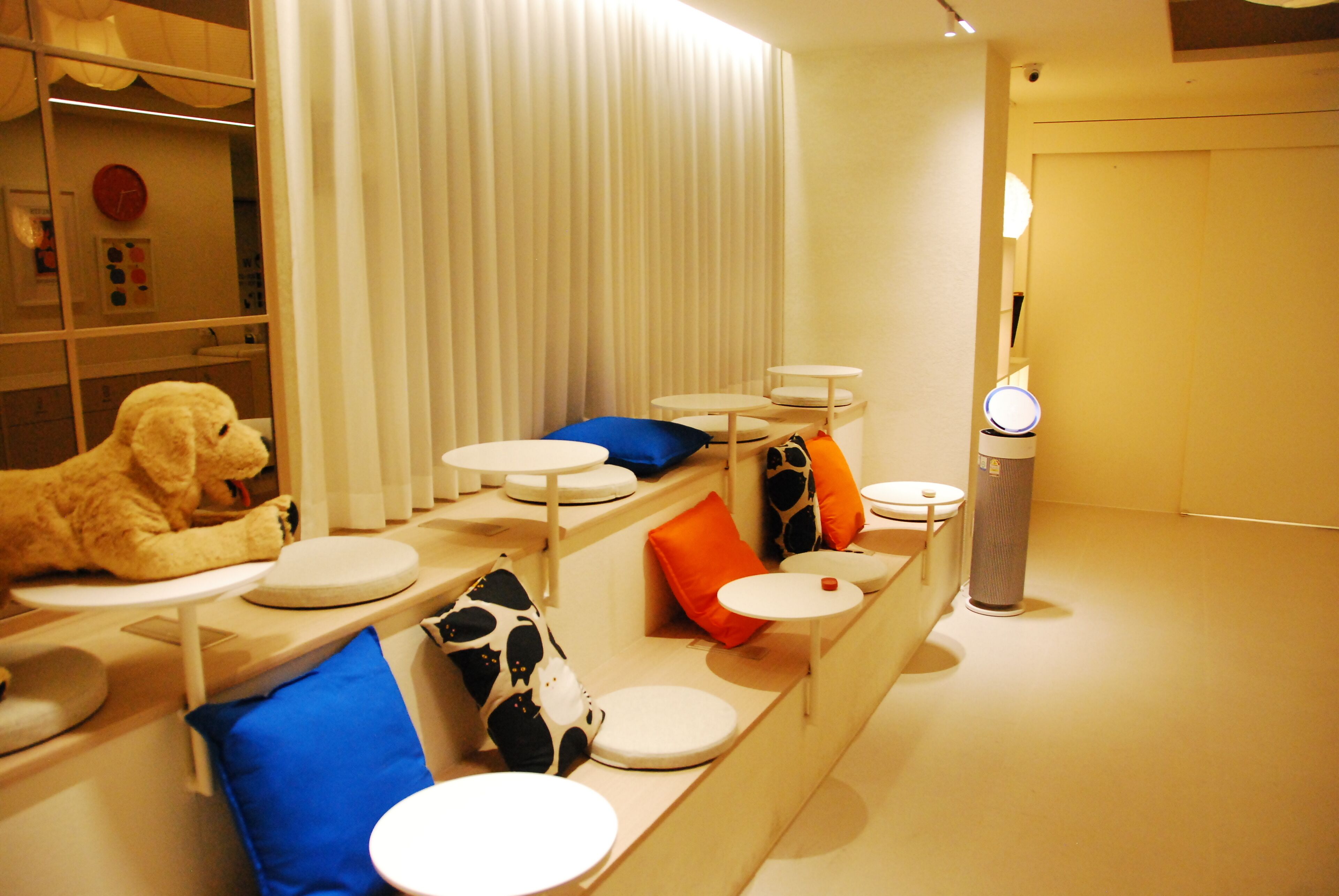 A modern hotel room with a sofa, a small table, and a trash bin.