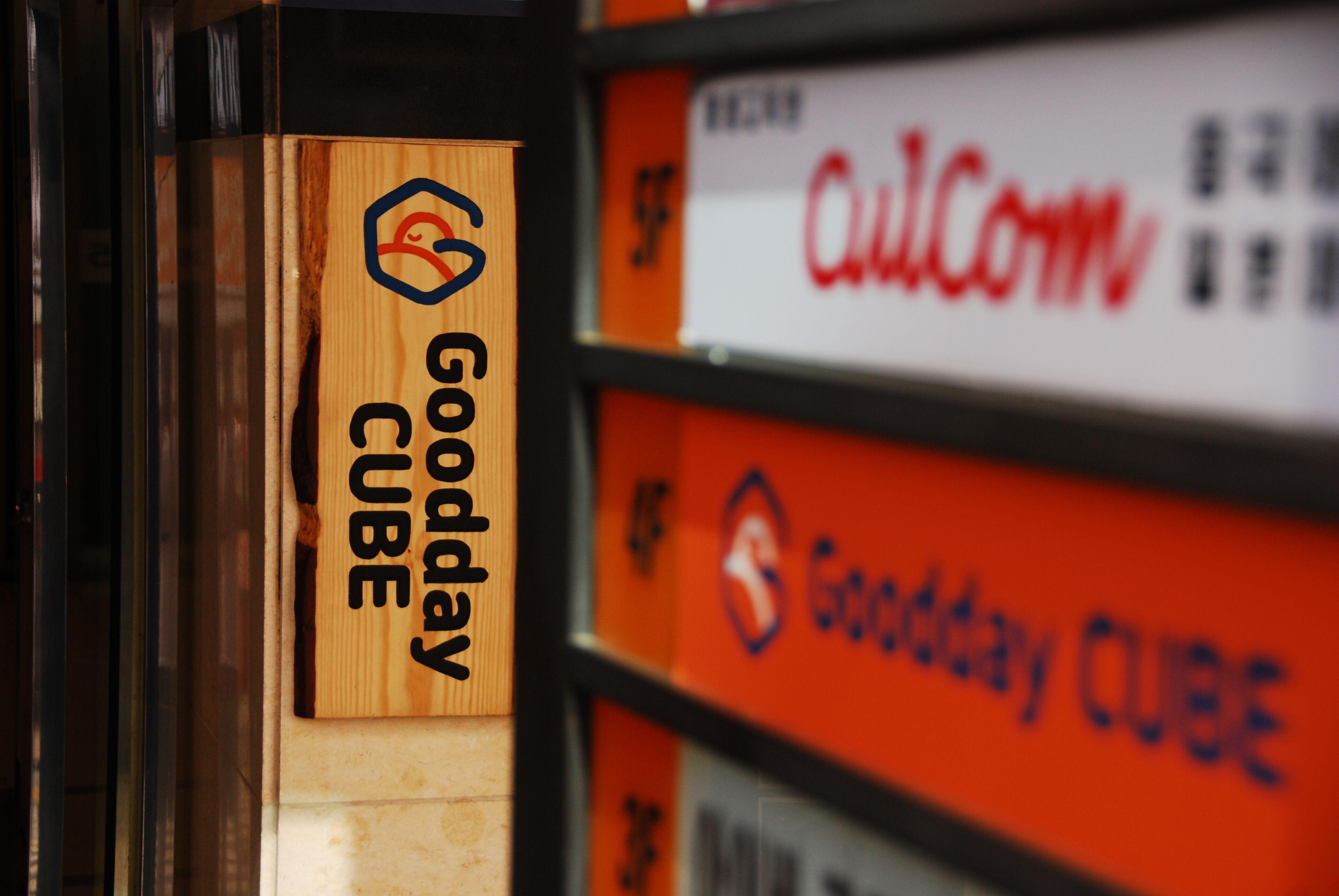 Ein Holzschild mit dem Text 'Goodday CUBE' und einem Logo.