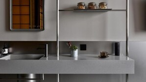 A modern kitchen with a built-in sink, a shelf with jars, a potted plant, and a cup. - NOA HOTEL XIAMEN (Xiamen)