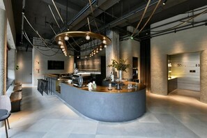 A modern bar area with a curved counter, stools, and a coffee machine. - NOA HOTEL XIAMEN (Xiamen)