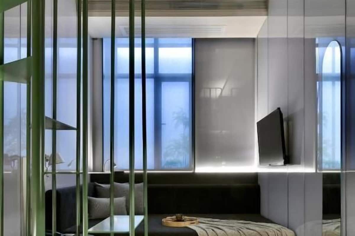 Un interior moderno con un sofá, una mesita y un televisor en un estante de pared.
