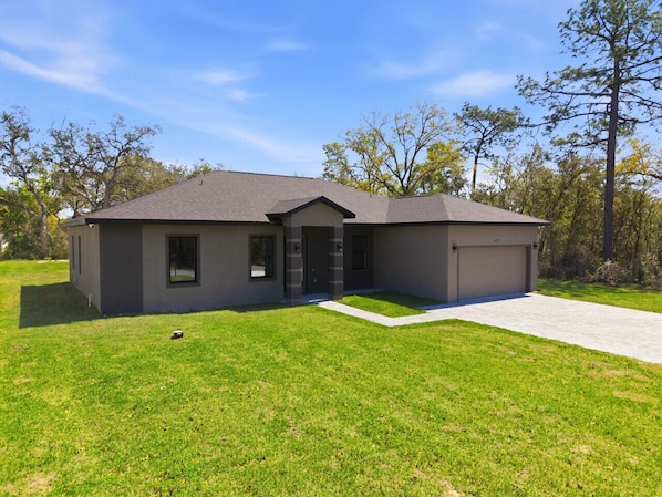 A modern two-story house with a garage, a front porch, and a well-maintained lawn.