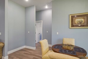 A hallway with a door, a round table with a placemat, and a framed picture on the wall.