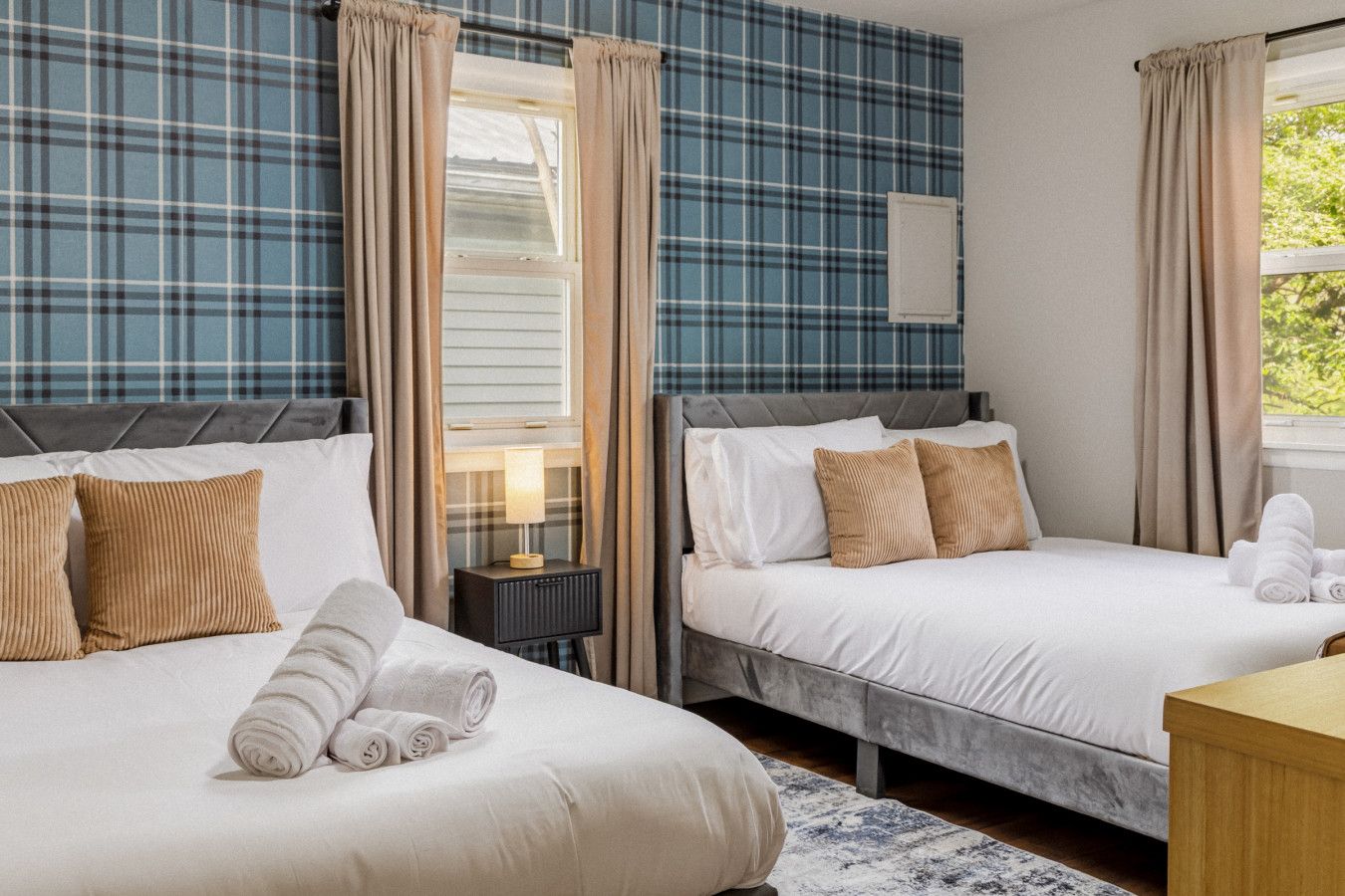 Ein Hotelzimmer mit zwei Betten, einem Nachttisch, einer Lampe und Wänden mit Karomuster.