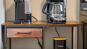 A kitchen counter with a coffee maker, a coffee filter container, and a sugar and tea container.