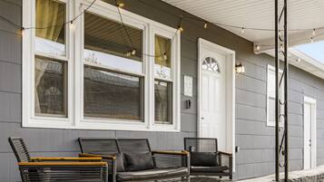 A building with a porch, two chairs, and string lights.