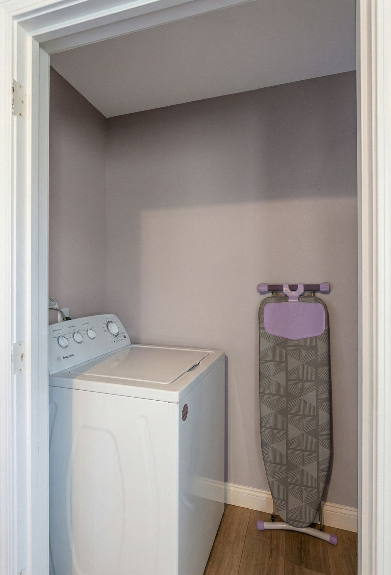 A laundry room with a washing machine and an ironing board.