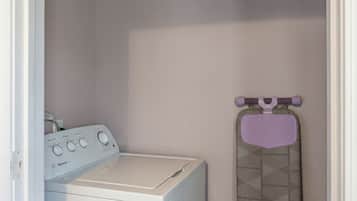 A laundry room with a washing machine and an ironing board.