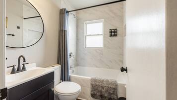 A modern bathroom with a toilet, sink, and bathtub.