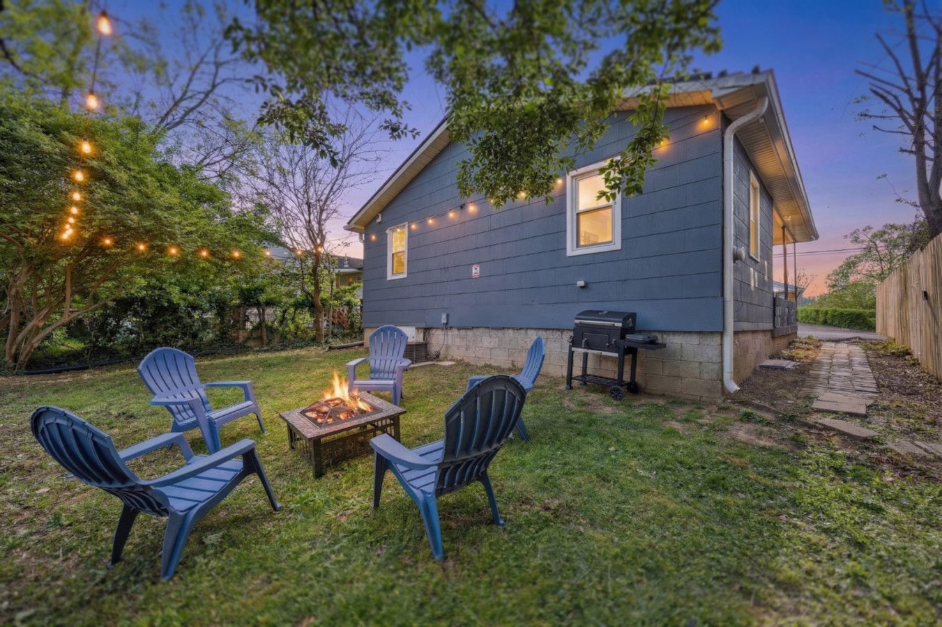Ein Garten mit Feuerstelle, Gartenmöbeln und Grill.