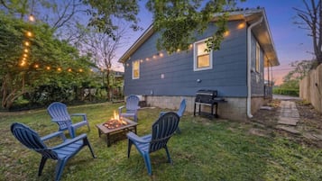 Ein Garten mit Feuerstelle, Gartenmöbeln und Grill.
