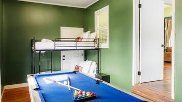 A room with a pool table, bunk beds, and a door leading to another room.