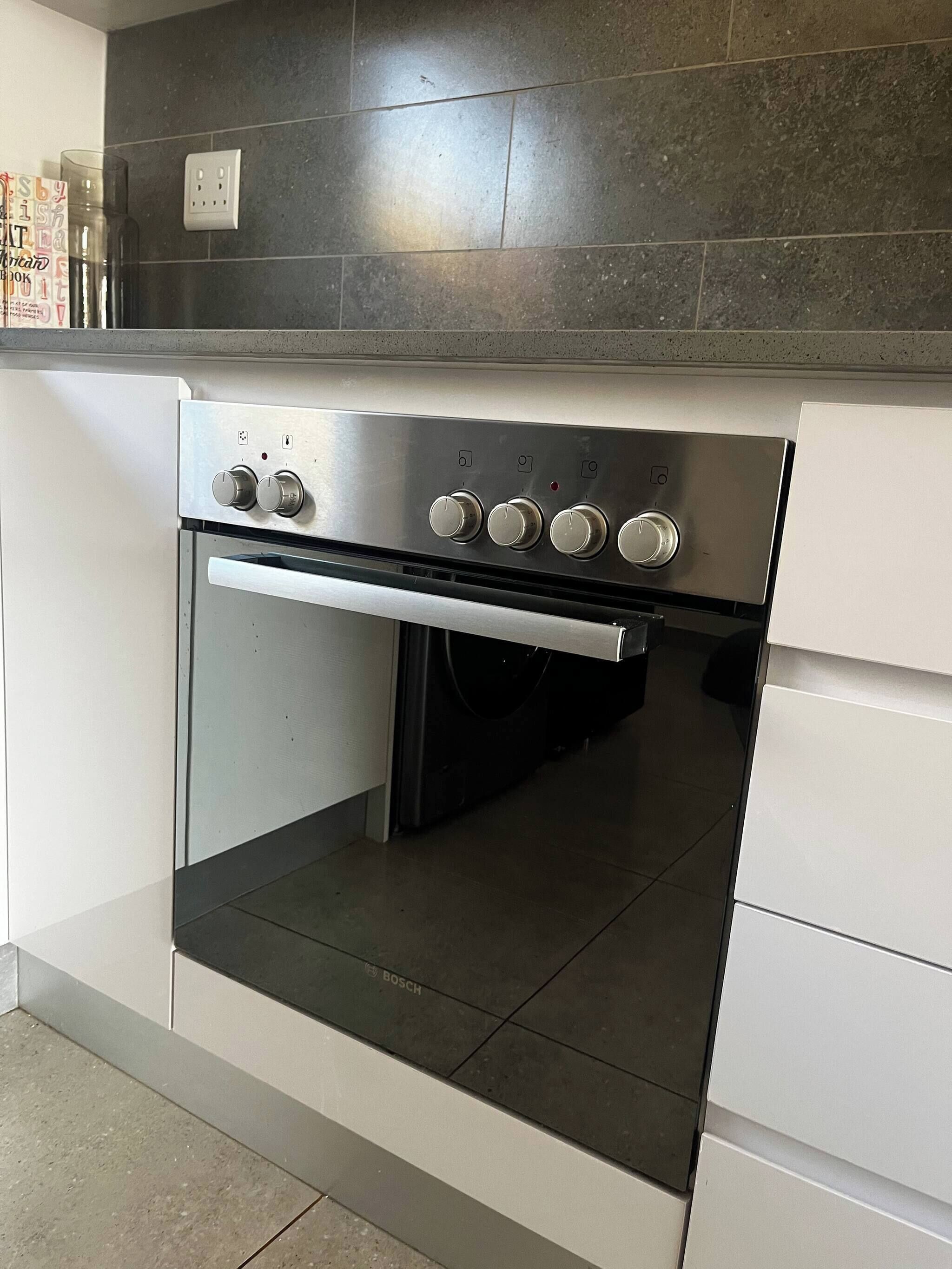 A kitchen with a Bosch oven, a tiled backsplash, and a white countertop.