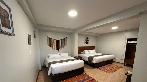 A hotel room with two beds, a wooden floor, and a colorful rug. - Hotel Boutique Qorikallpa (Cusco)