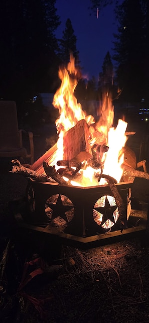 A campfire with logs and a star-shaped metal container.