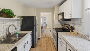 A kitchen with white cabinets, a black refrigerator, a microwave, and a stove. - Big Group Getaway Near OSU with 6BR, 8 Beds, 5-Car Parking (Columbus)