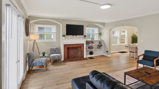 A spacious living room with a fireplace, a flat-screen TV, and a dining area with a table and chairs. - Big Group Getaway Near OSU with 6BR, 8 Beds, 5-Car Parking (Columbus)