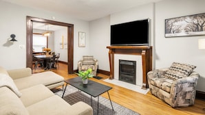 A living room with a fireplace, a flat-screen TV, and a dining area with a table and chairs.