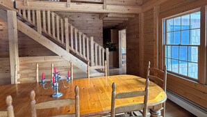 Un interior de madera con una mesa de comedor, sillas, una escalera y una ventana.