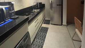 A modern kitchen with a microwave, stove, refrigerator, and a dishwasher. - Casa Vertice – Copacabana (Uberlândia)
