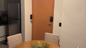 A modern kitchen with a built-in refrigerator, a wooden door, and a round dining table with a glass bowl centerpiece. - Casa Vertice – Copacabana (Uberlândia)