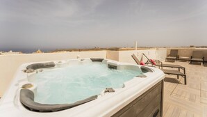 A hot tub on a rooftop terrace with a view of the ocean and distant buildings. - Luxury Penthouse Jacuzzi BBQ Terrace Pool Table (Xaghra)