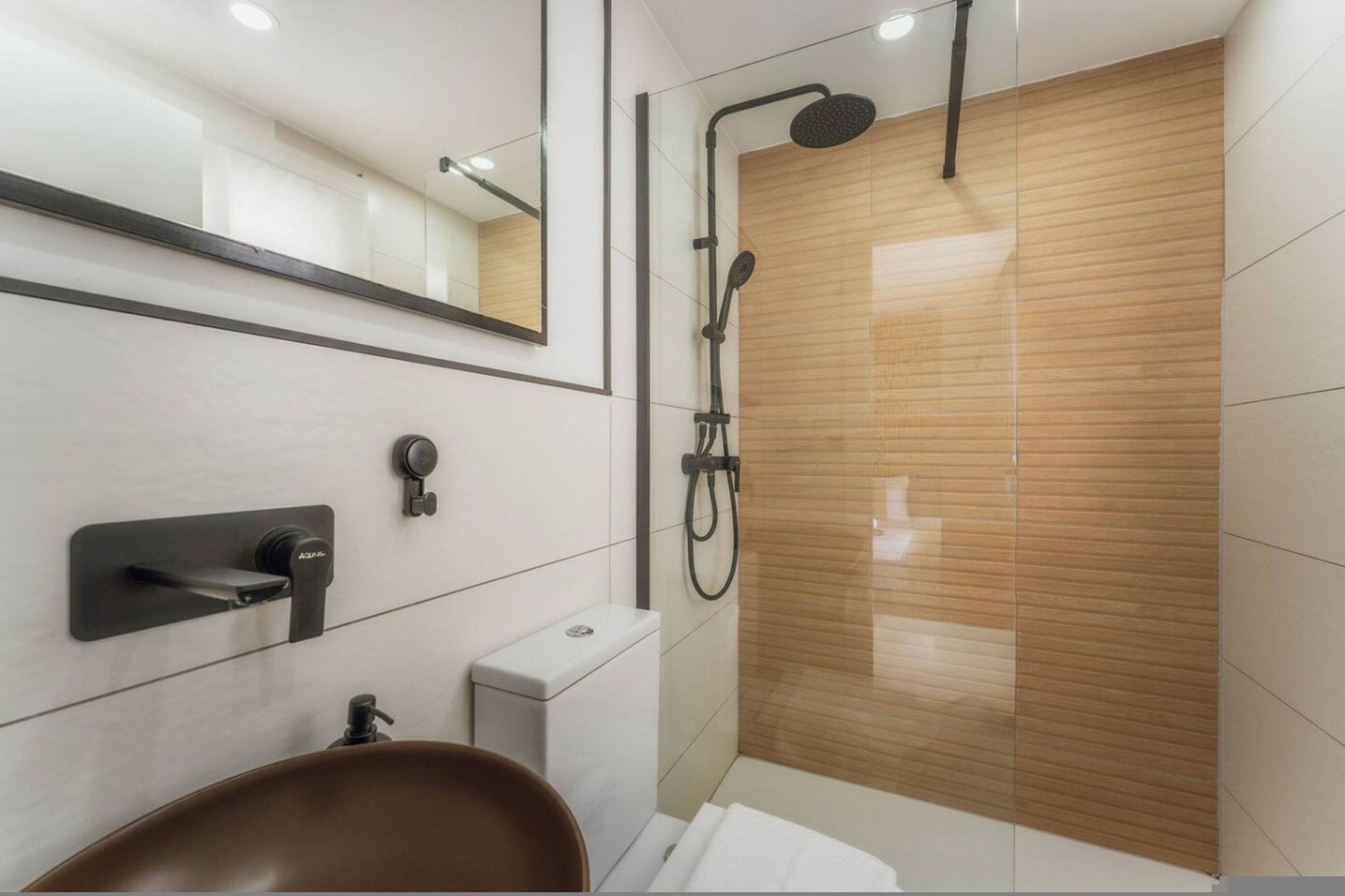 Un baño moderno con inodoro, lavabo, espejo y ducha.