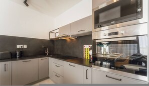 A modern kitchen with stainless steel appliances, a built-in oven, and a microwave. - Luxury Penthouse Jacuzzi BBQ Terrace Pool Table (Xaghra)