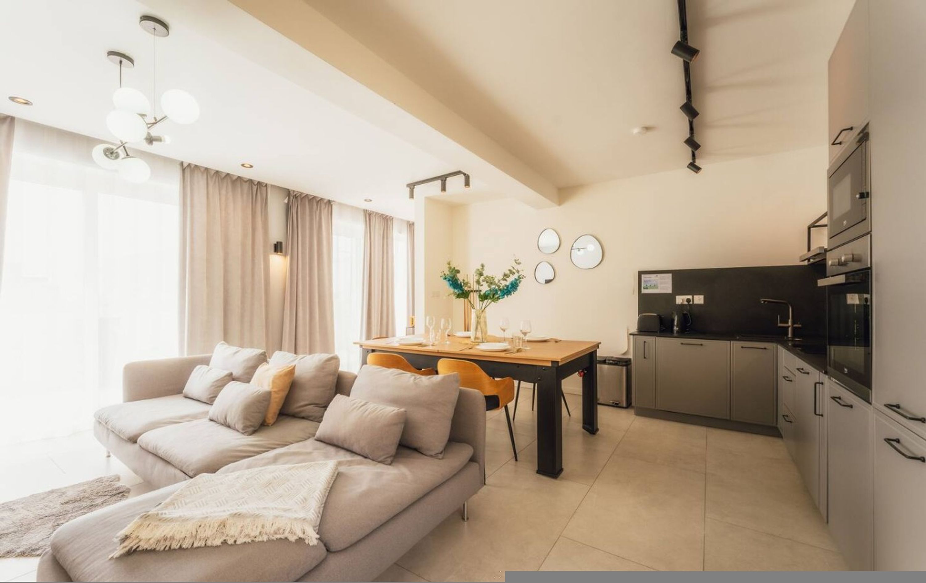Una sala moderna con sofá, mesa de comedor y zona de cocina.