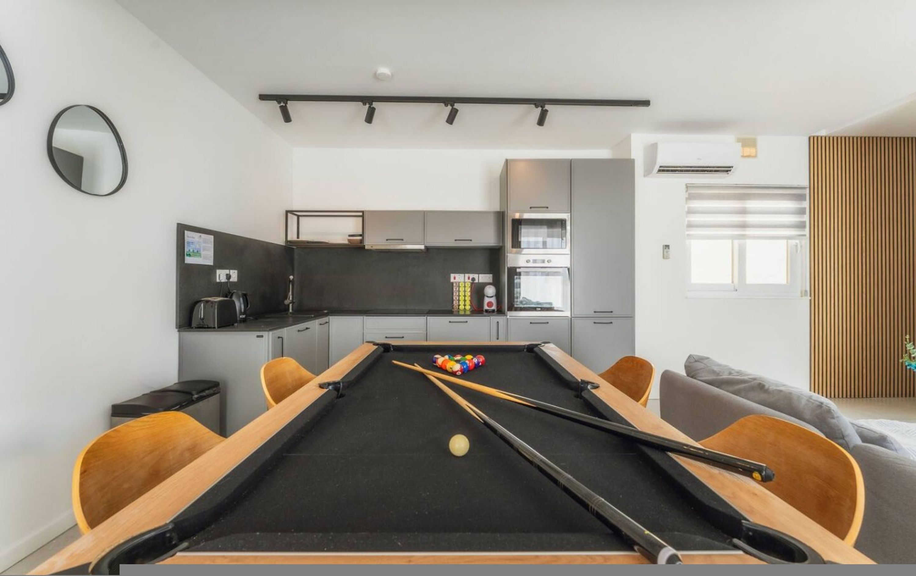 Un espace de vie moderne comprenant une table de billard, une cuisine et un coin salon.