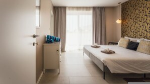 A hotel room with a bed, a desk, a chair, a window with curtains, and a patterned wall. - Luxury Penthouse Jacuzzi BBQ Terrace Pool Table (Xaghra)