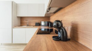 Une cuisine moderne avec un plan de travail en bois, une bouilloire, un grille-pain et un verre.