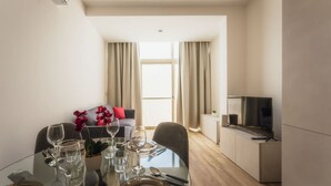 Un coin repas avec une table en verre, des chaises et un canapé en arrière-plan.