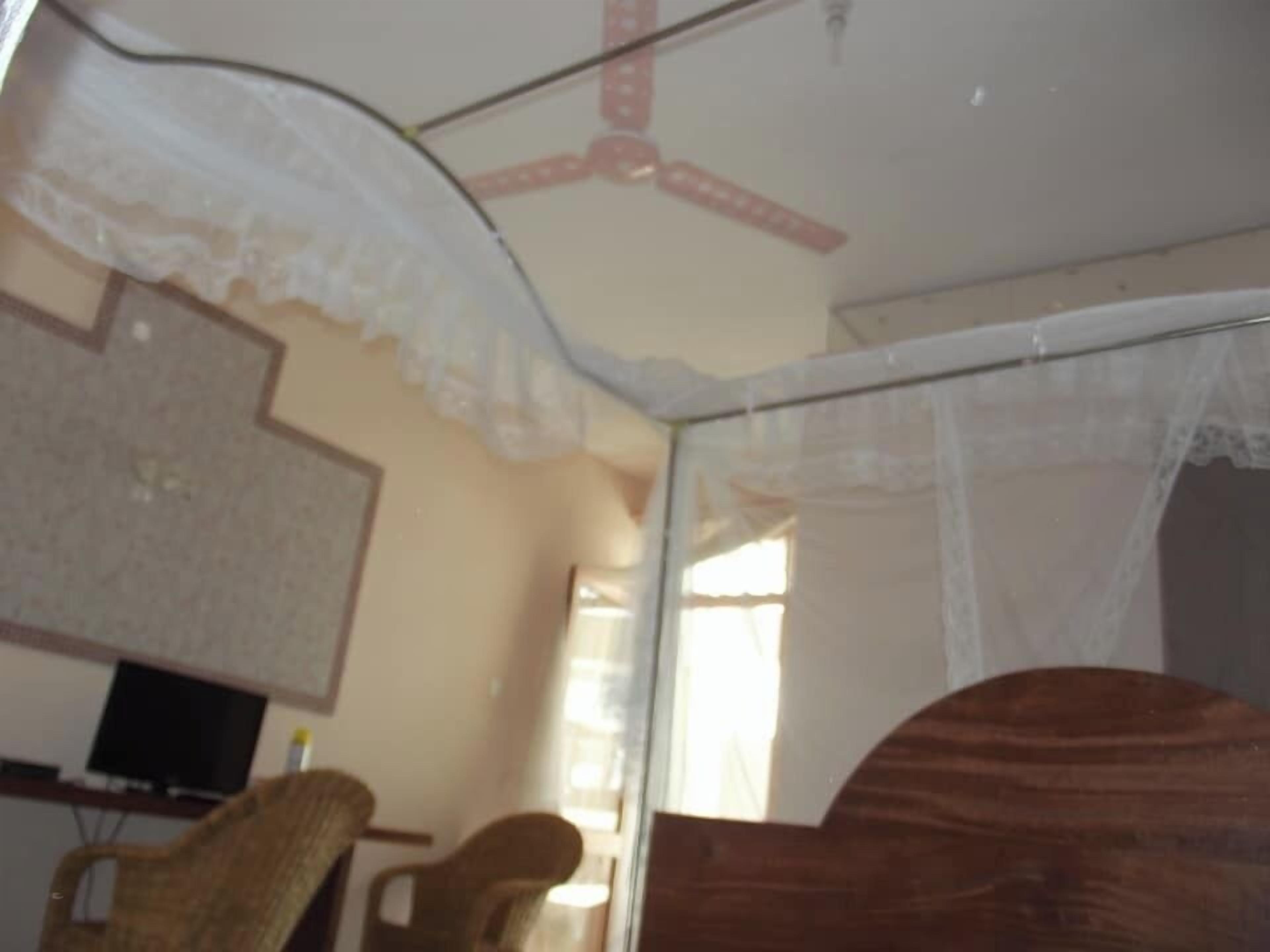 Una habitación con una cama, una silla, un televisor y una ventana.