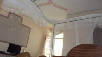 Una habitación con una cama, una silla, un televisor y una ventana.