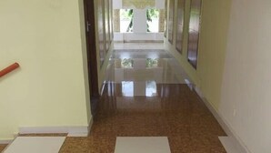 A hallway with a shiny tiled floor, a door on the left, and a window on the right.