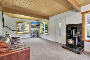 Una sala de estar acogedora con chimenea, un sofá de cuero y ventanas amplias que ofrecen vistas al exterior.