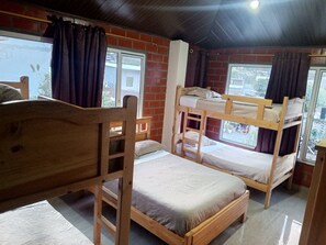 A room with bunk beds, a wooden chair, and a window with curtains.