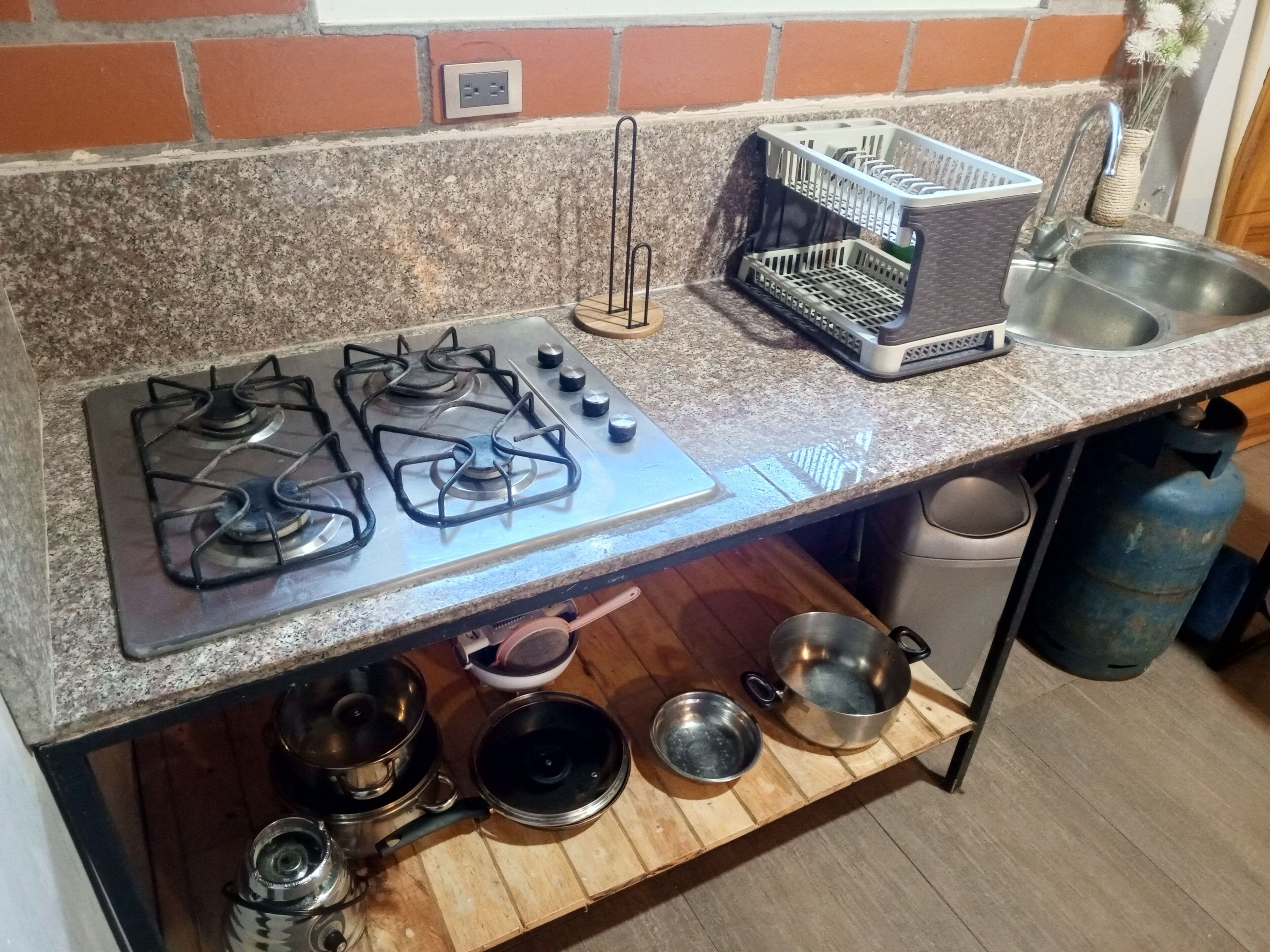 Eine Küche mit Gasherd, Geschirrgestell, Spüle und Gasflasche.