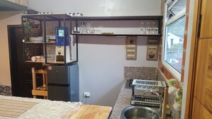 A compact kitchen with a bed, a water dispenser, a sink, and a window with a view.