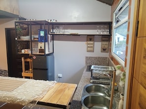 A compact kitchen with a bed, a water dispenser, a sink, and a window with a view.