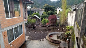 A courtyard with a brick building, a wooden bench, and a small garden area with plants and a curved brick structure.