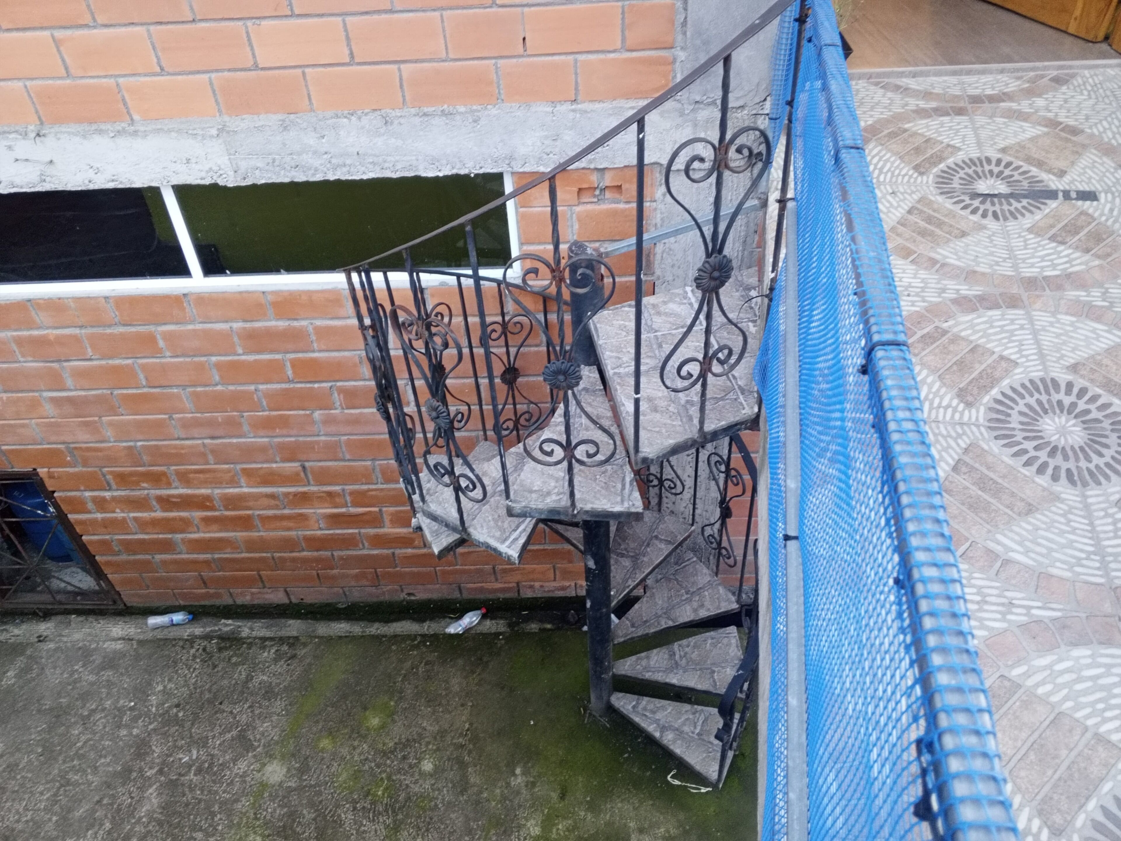 Un escalier avec des rampes en métal, un mur en briques et un sol à motifs.
